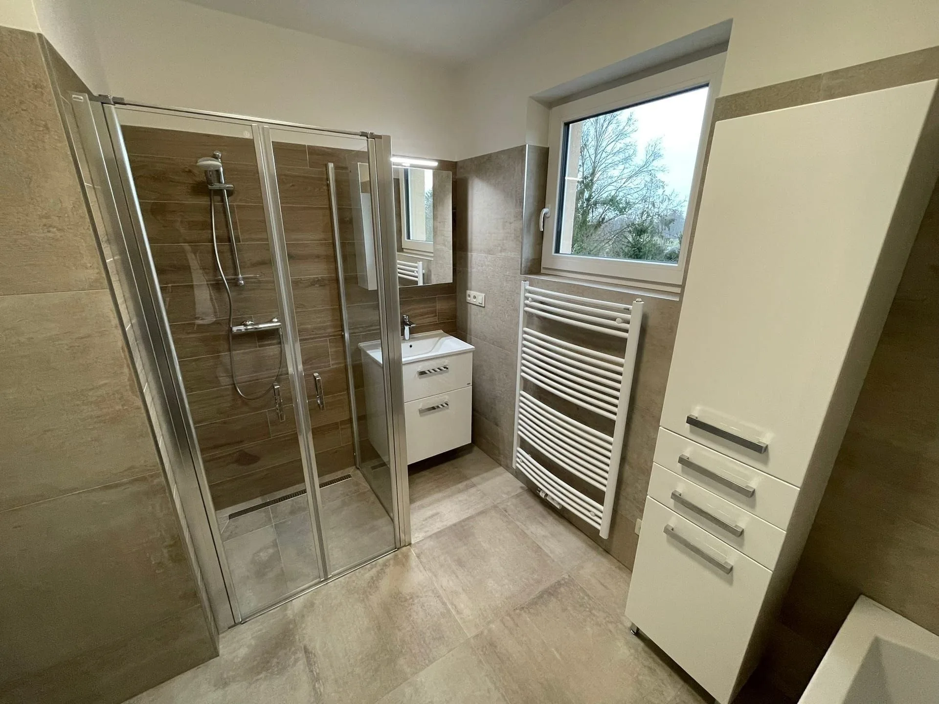 Completed bathroom with a shower enclosure and storage
